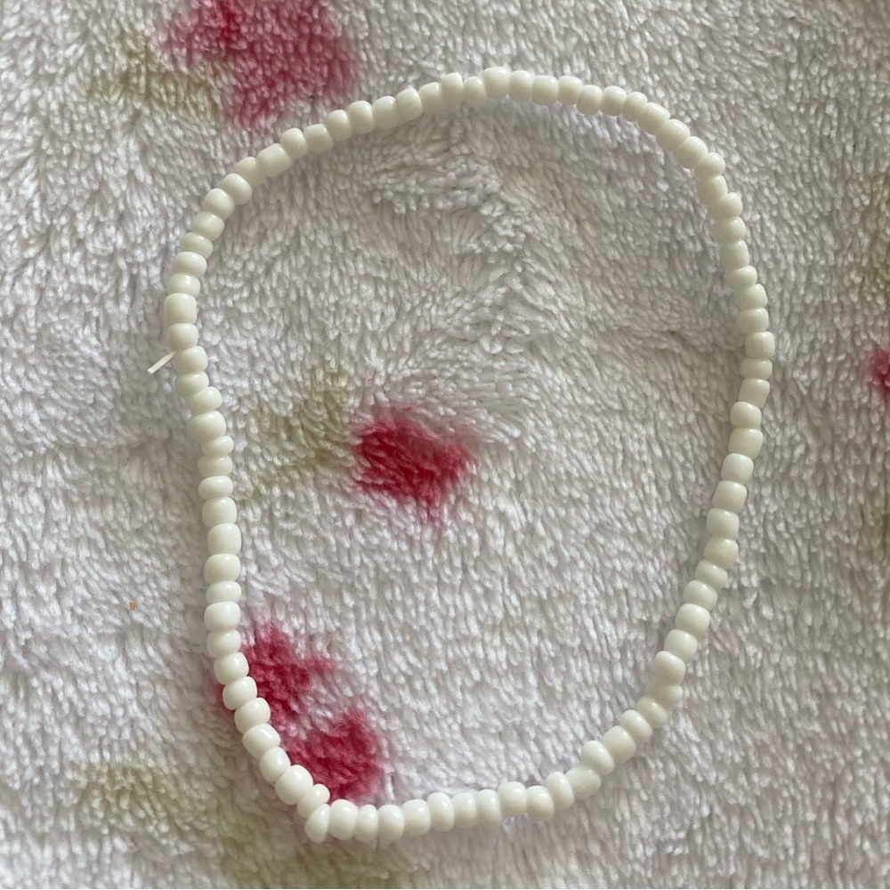 A white color seed bead style ankle bracelet .
